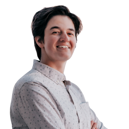 Smiling person with short dark hair wearing a light patterned button-down shirt, arms crossed against a white background.